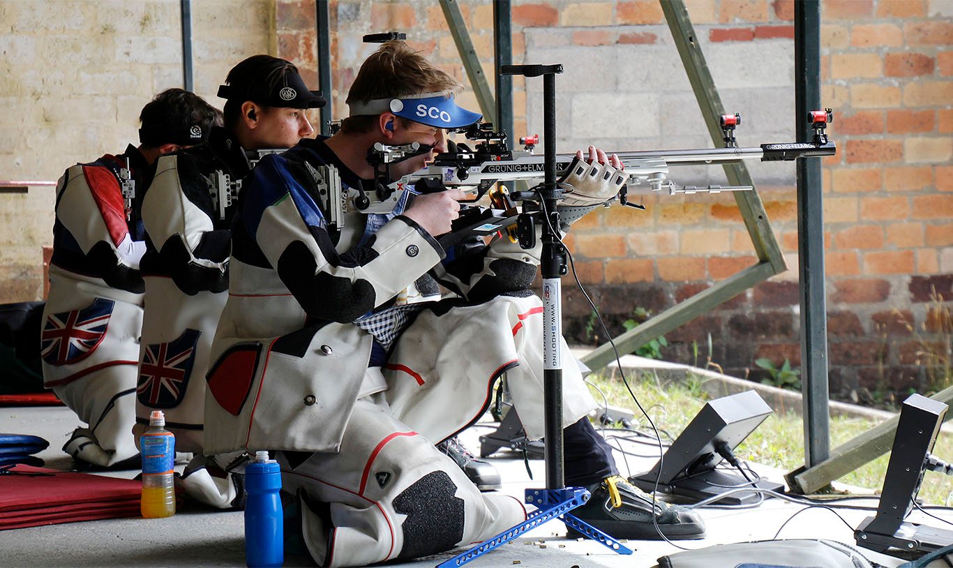 A group of athletes aim target rifles in the kneeling position at an outdoor competition. Photo: Niall Evans