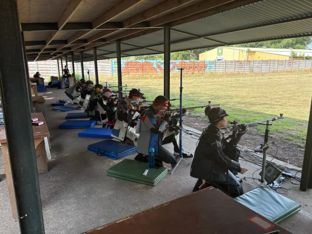 A group of target shooters compete form the kneeling position on an oudoor rifle range.