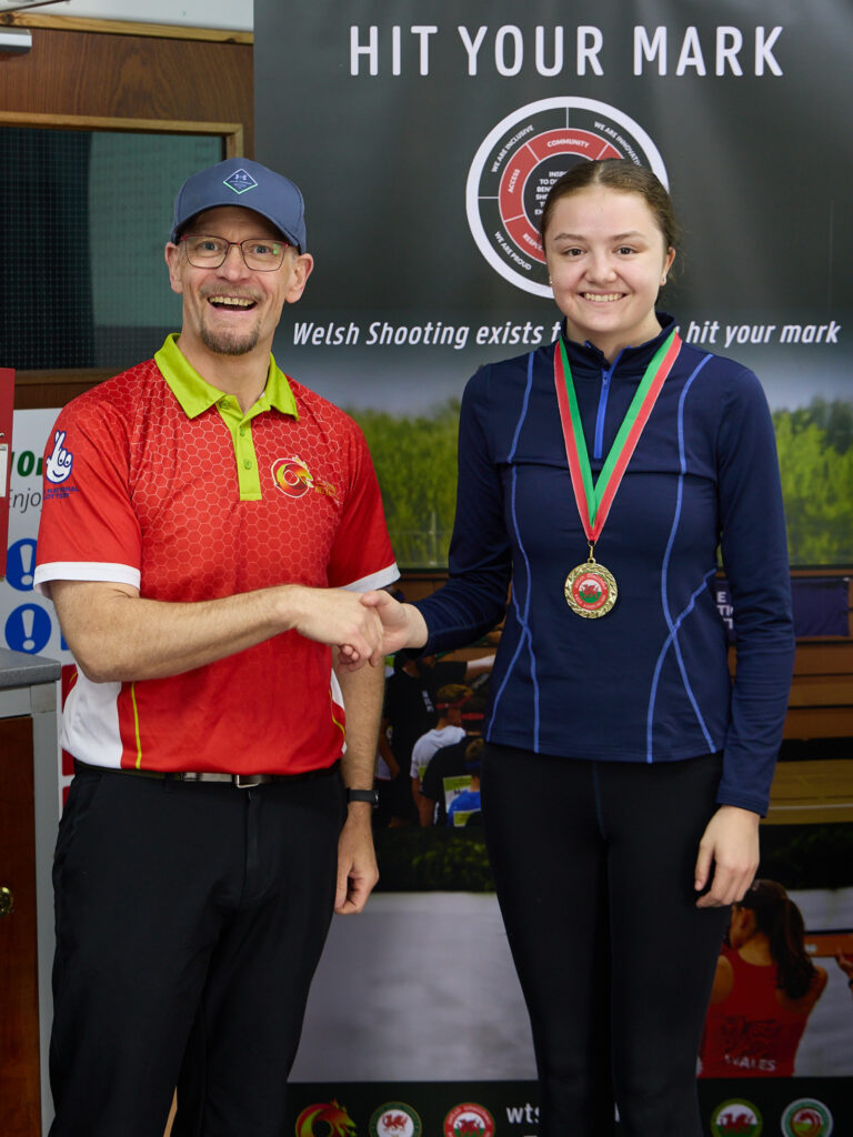 Two smiling people pose during a medal presentation.