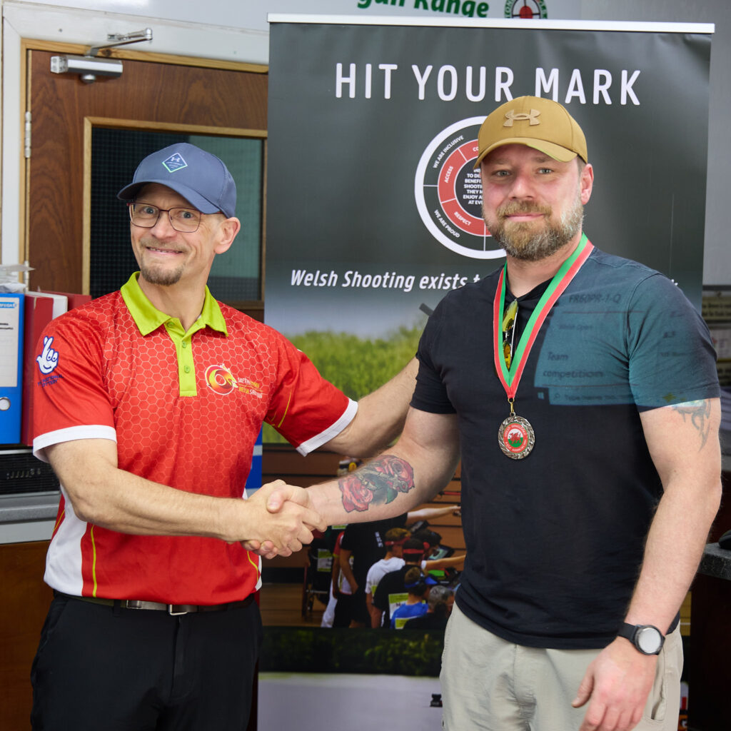 Two smiling people pose during a medal presentation.