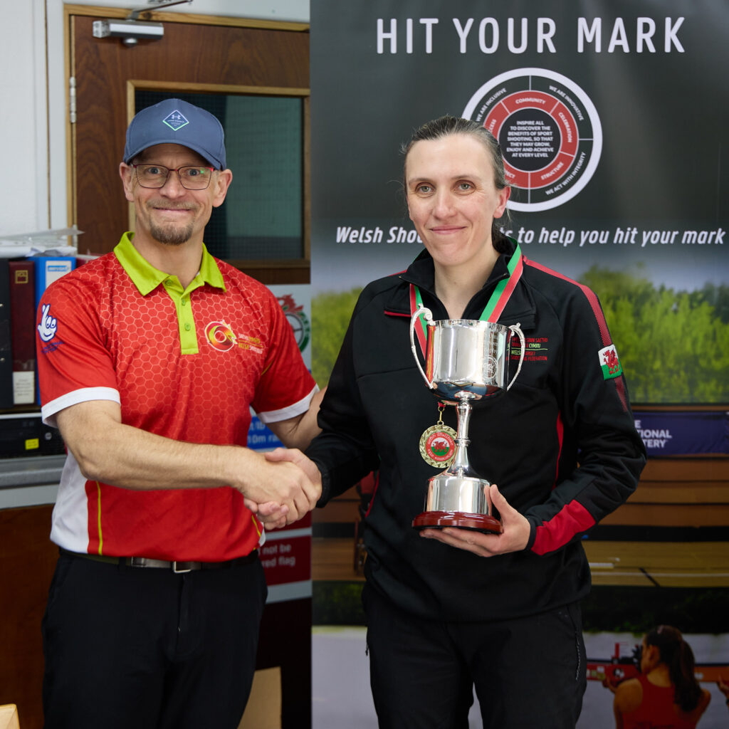 Two smiling people pose during a medal presentation.