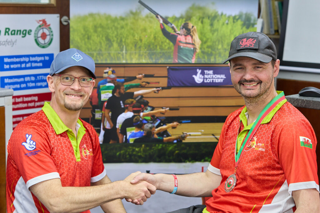 Two smiling people pose during a medal presentation.